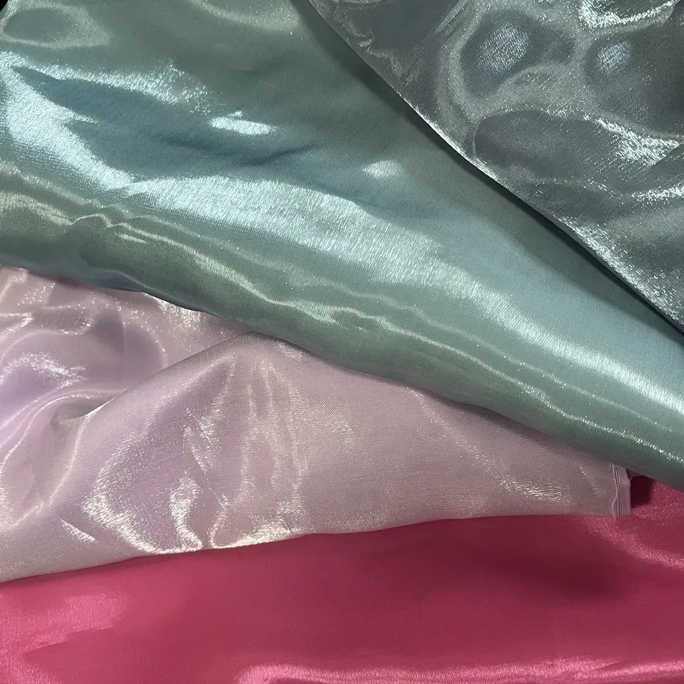 An image of 4 liquid metal or liquid satin fabric in pink, sage green, grey and baby pink colors